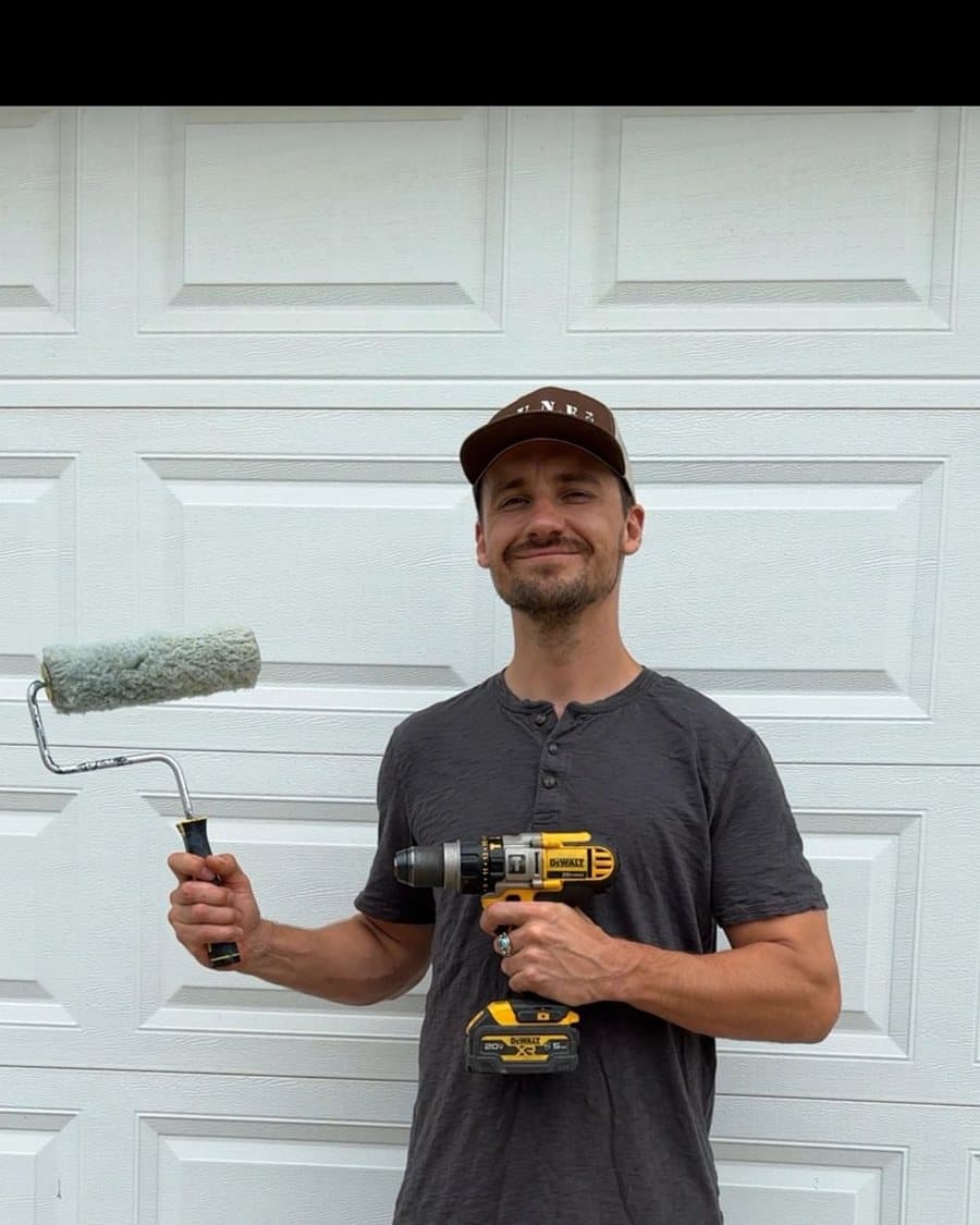 Alex holding a paint roller and a cordless drill
