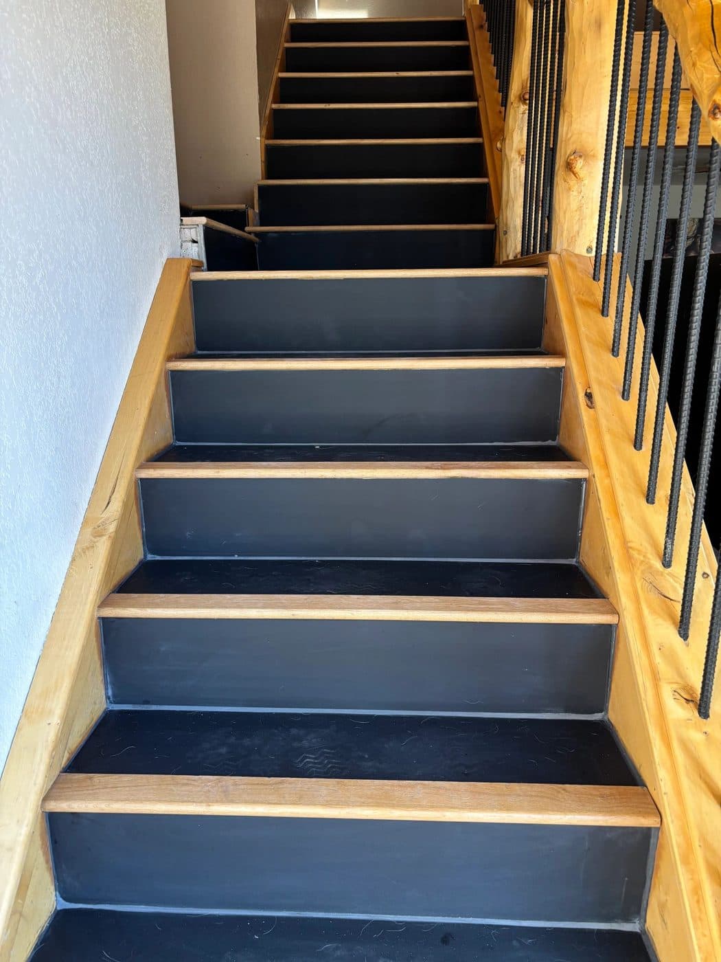 A staircase with dark large-format tile treads and a wood bullnose edge